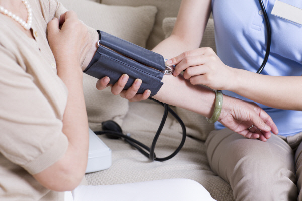 Nursingassistanttakingseniorwoman`sbloodpressure