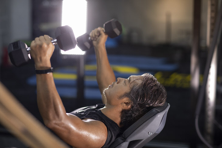 Mature man working out with hand weights at gym