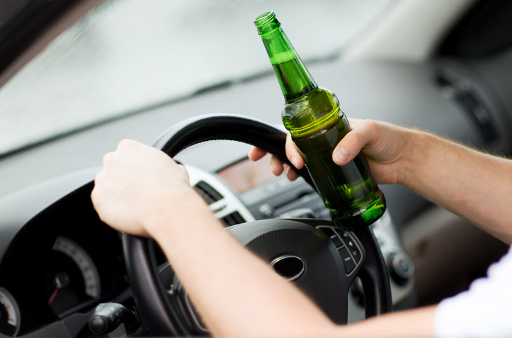 man drinking alcohol while driving the car